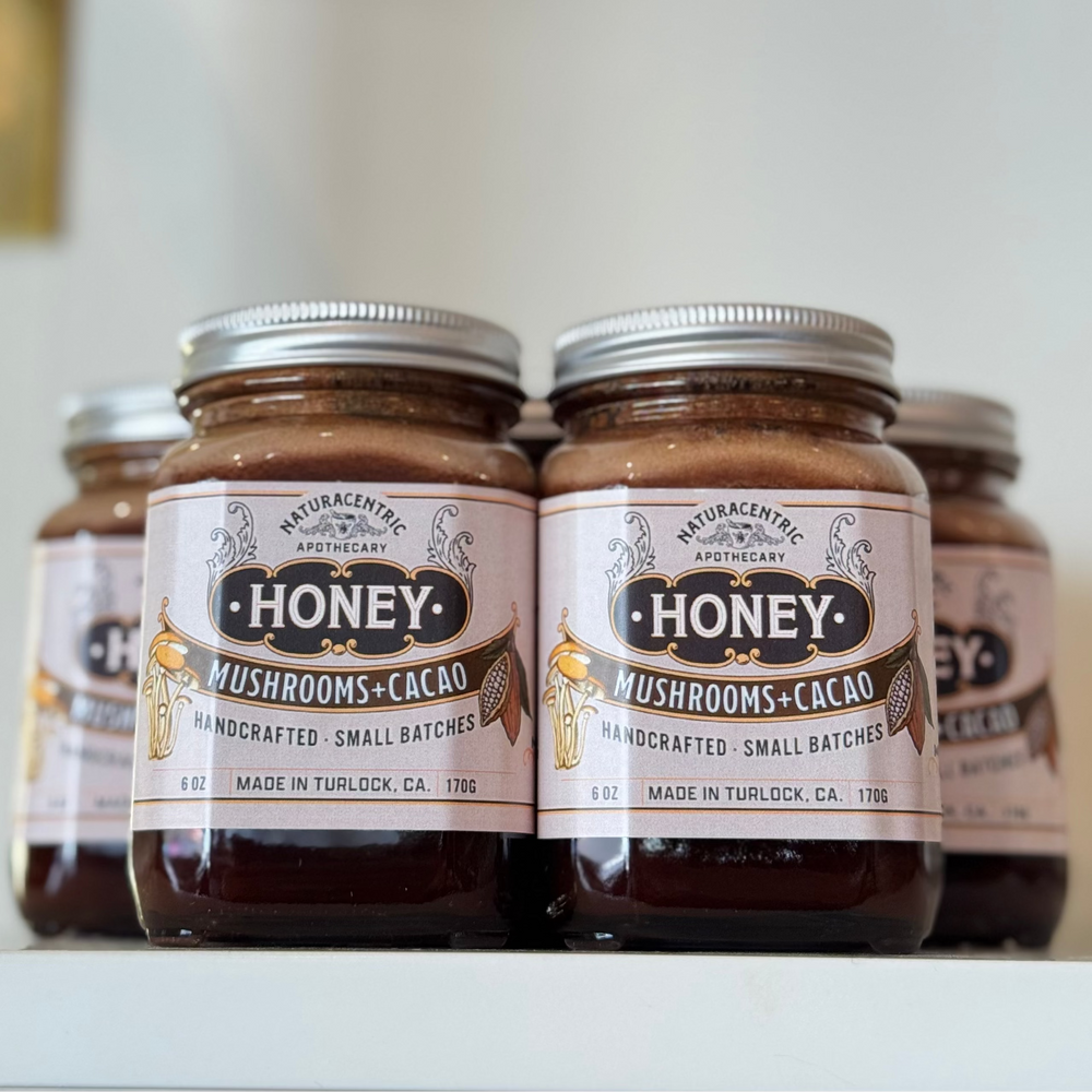 Jars of honey with mushroom and cacao flavor on a white surface.