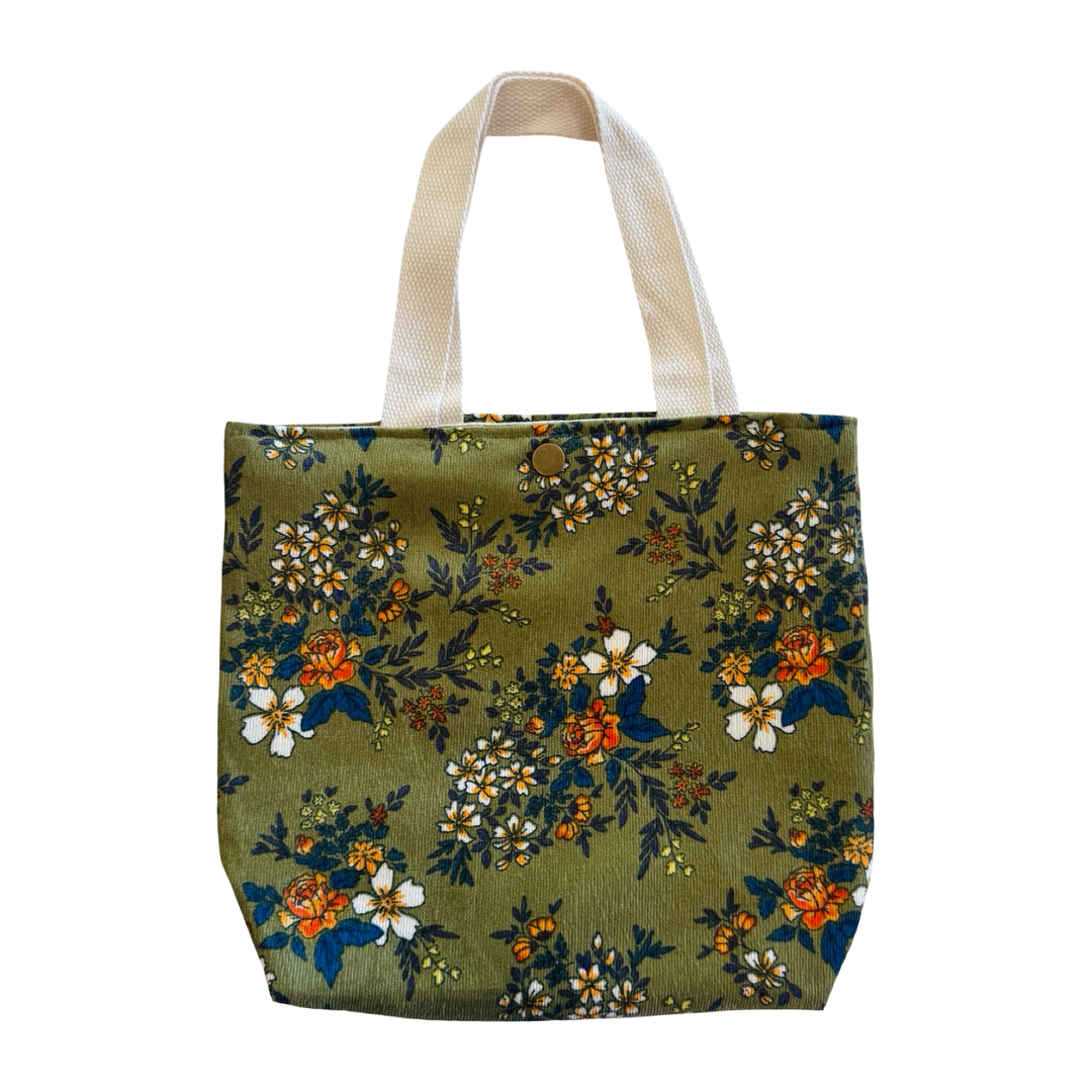 Mini green corduroy tote bag with small floral print, fabric handles, and a snap closure.