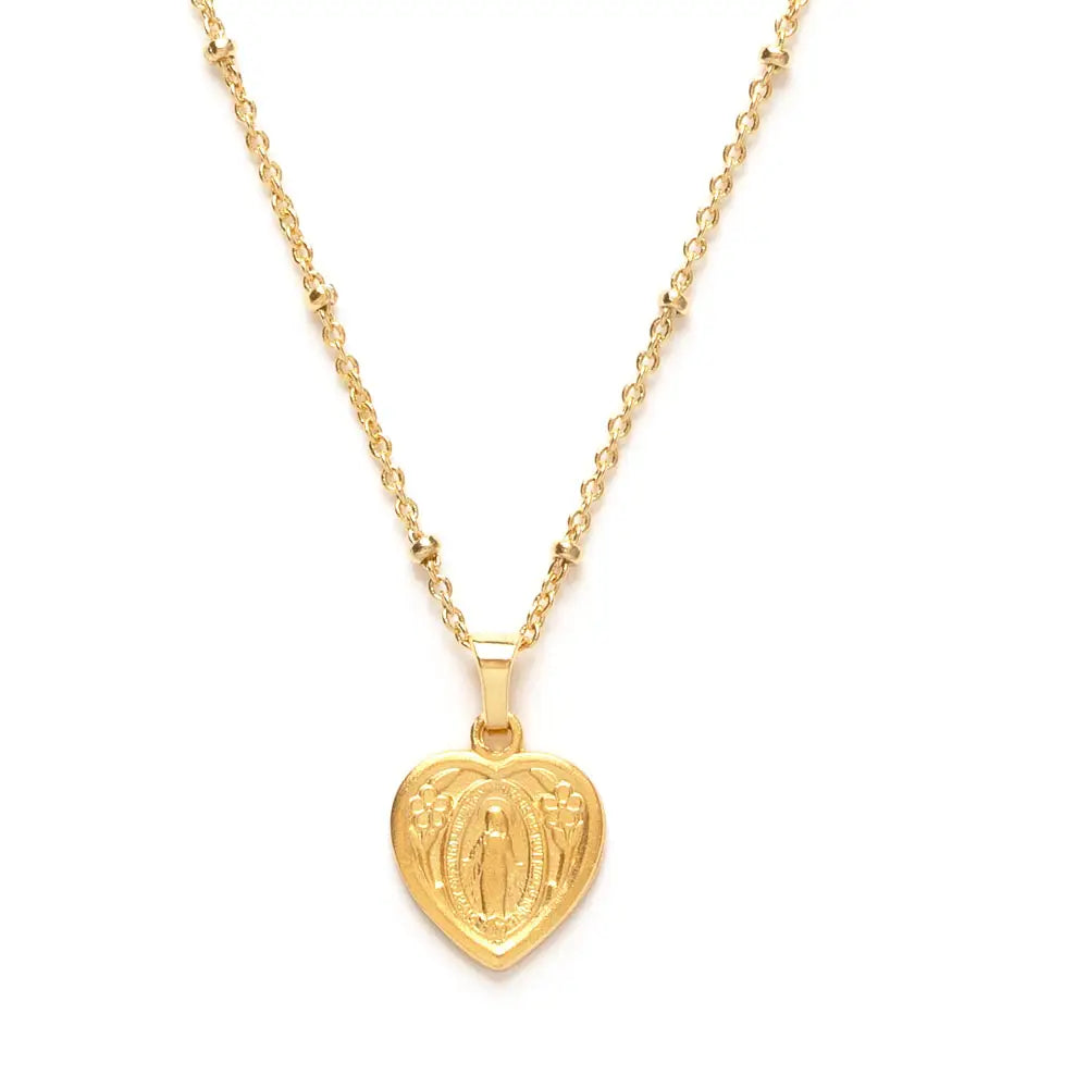 Close-up of gold heart-shaped Miraculous Mary medallion pendant with floral engravings, hanging on a fine beaded chain.