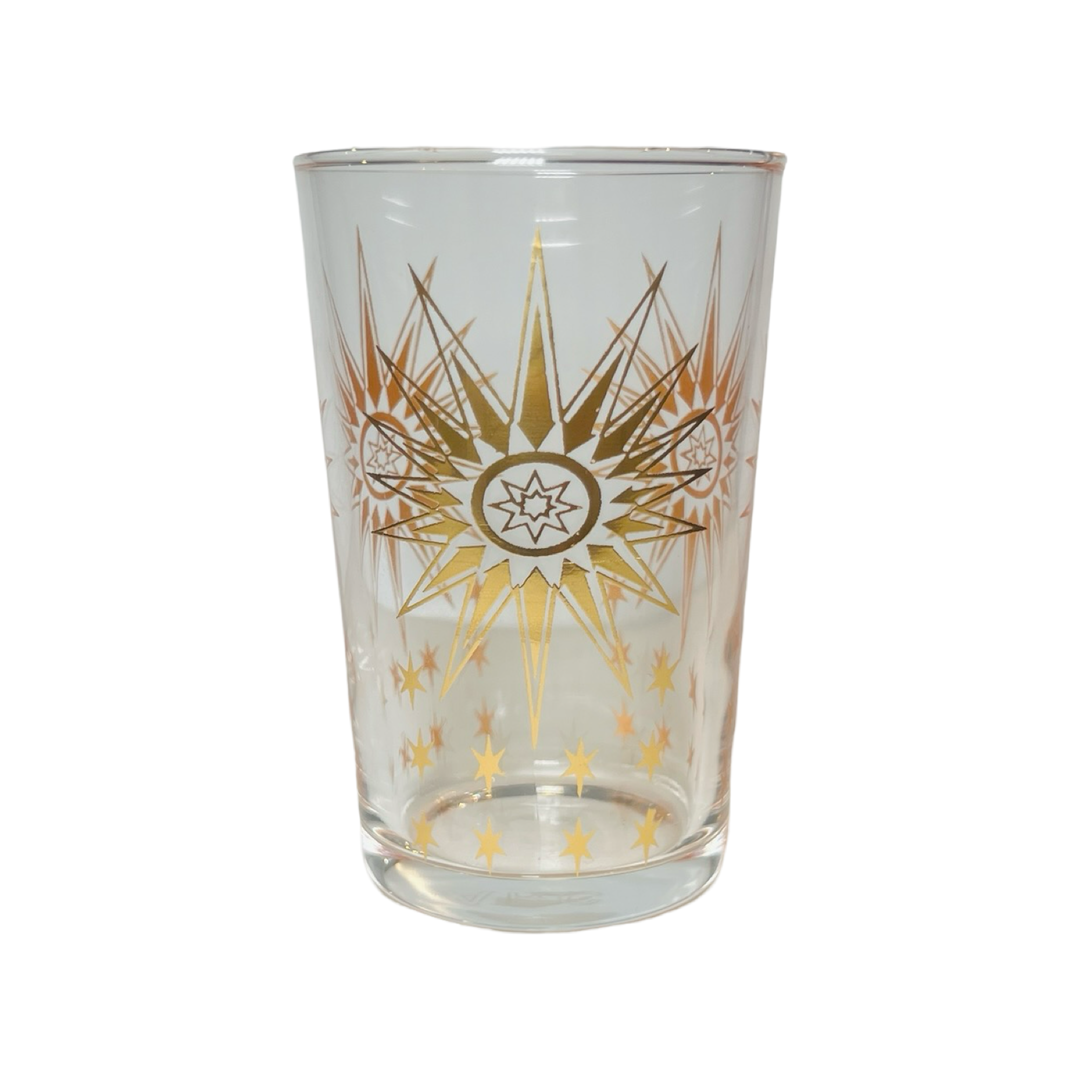 A clear glass tea glass with hand-painted gold stars and a geometric star pattern.