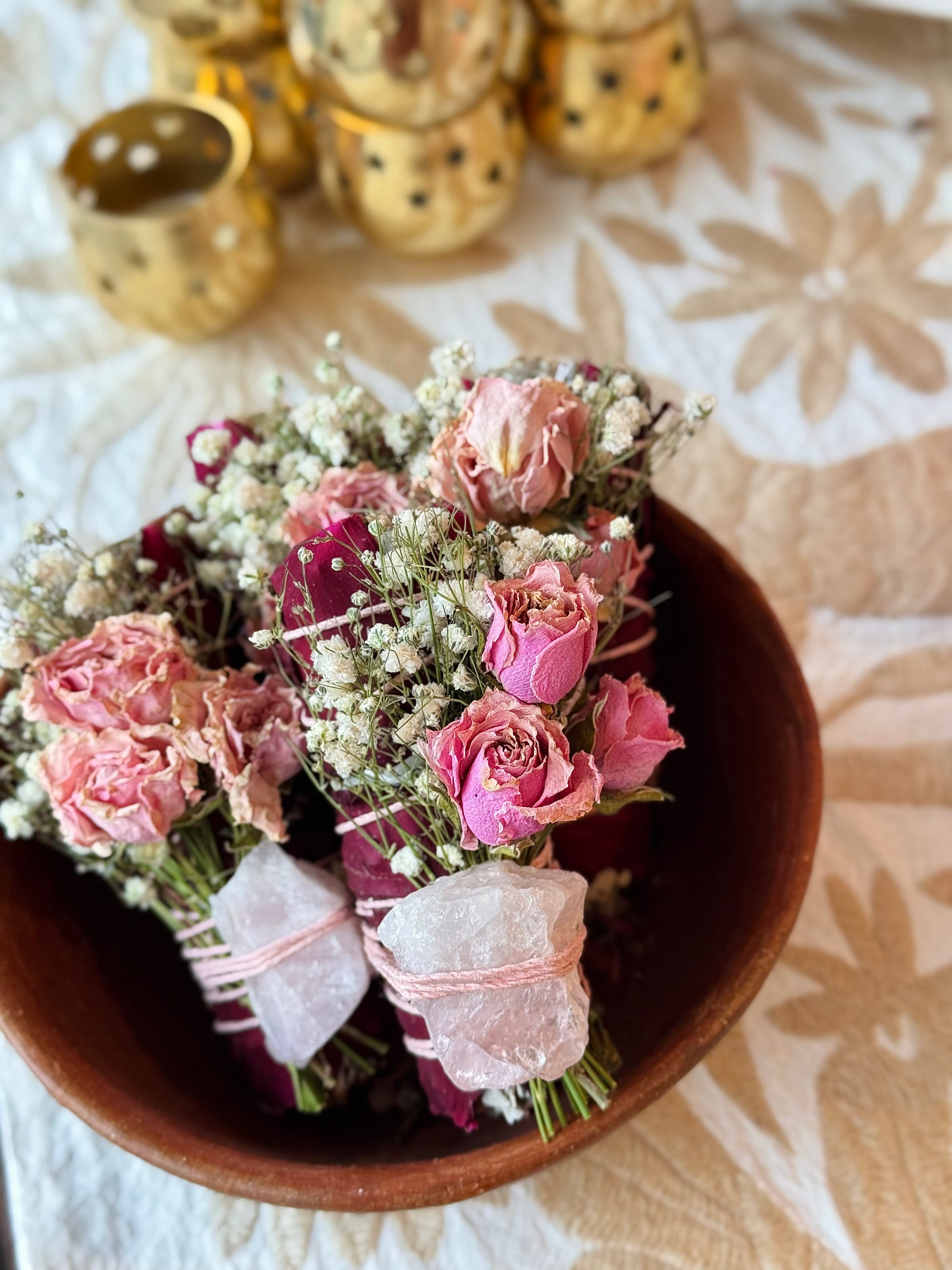 Bouquet of pink roses and white baby's breath in a terracotta pot on a floral tablecloth.