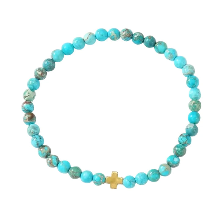 A turquoise imperial jasper stretch bracelet with natural brown veining and a small gold cross bead centerpiece.