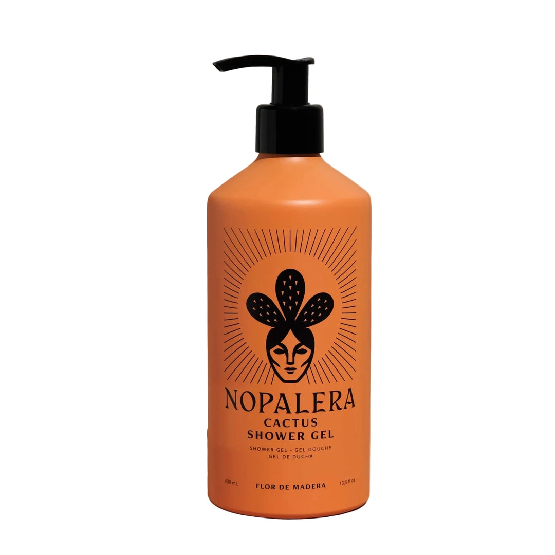 An orange pump bottle of Nopalera Cactus Shower Gel with a black pump dispenser, set against a solid peach-colored background with a soft shadow cast to the left.