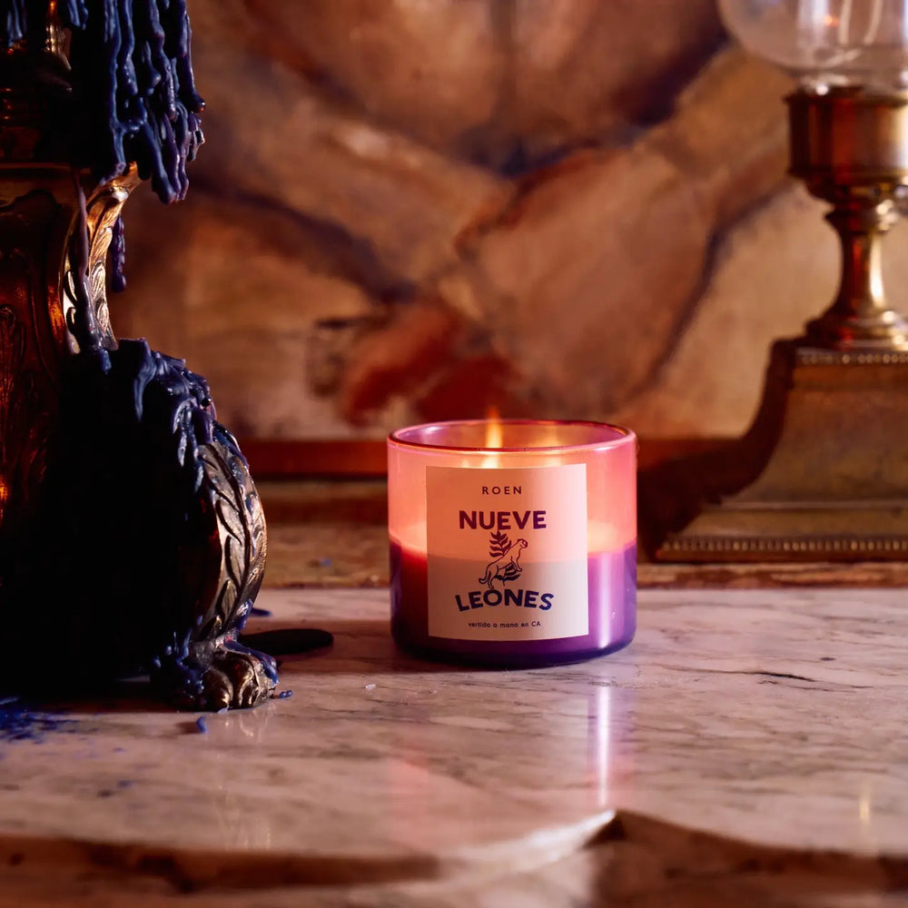 Photo of burning Nueve Leones candle on a marble tabletop. 