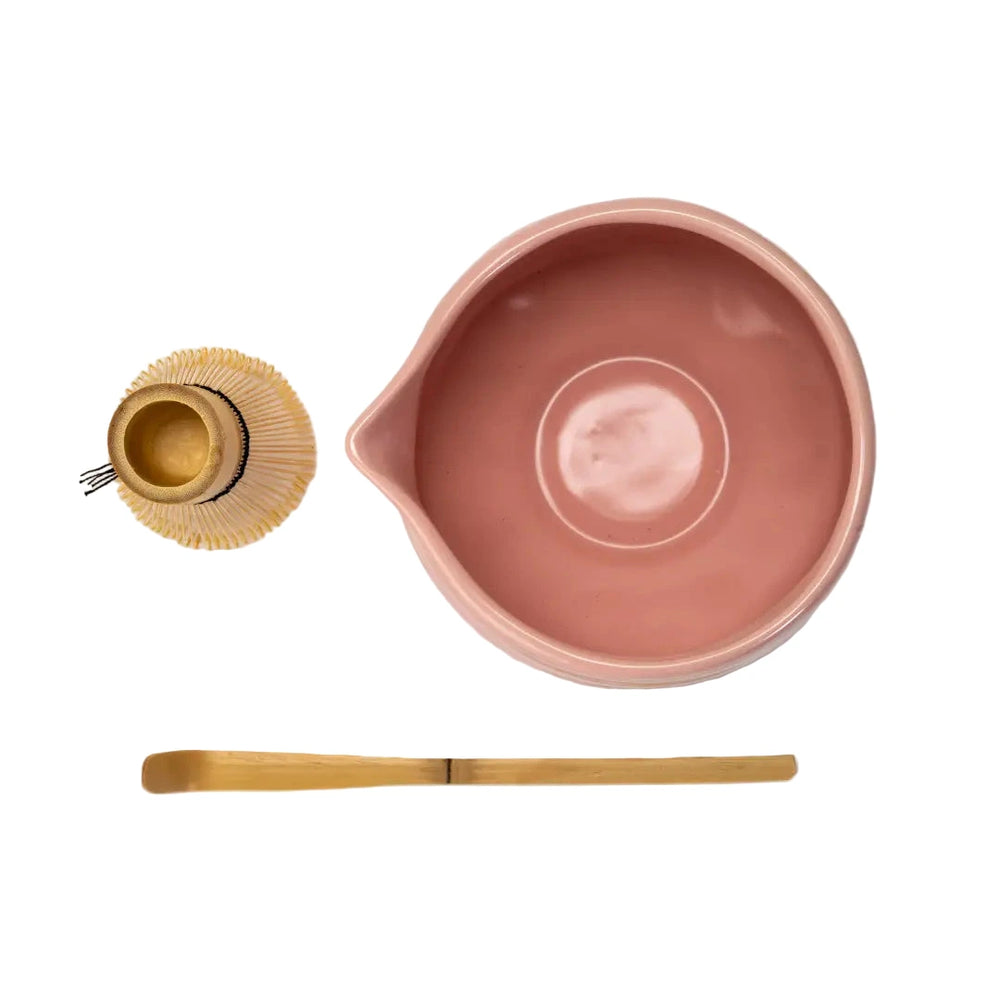 Top view of a pink matcha bowl, whisk and bamboo spoon.