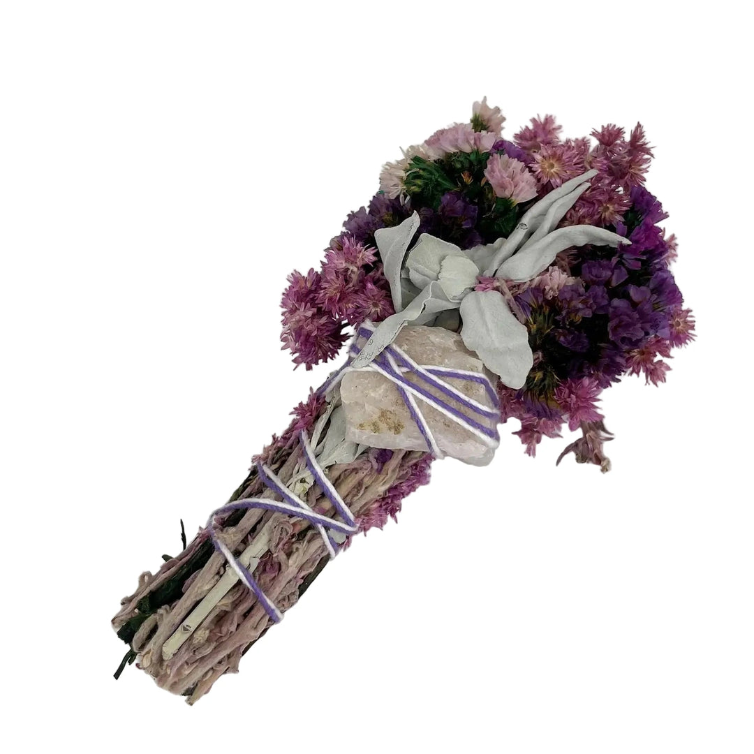 Hand-tied bundle of white sage with pink and purple dried flowers and a raw quartz crystal, wrapped in lavender string.