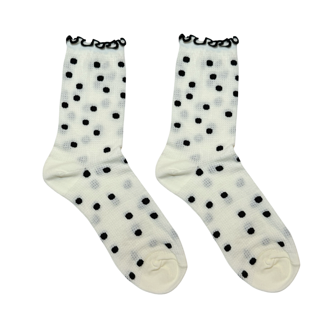 Pair of cream socks with black polka dots and a black ruffle trim on the cuff.