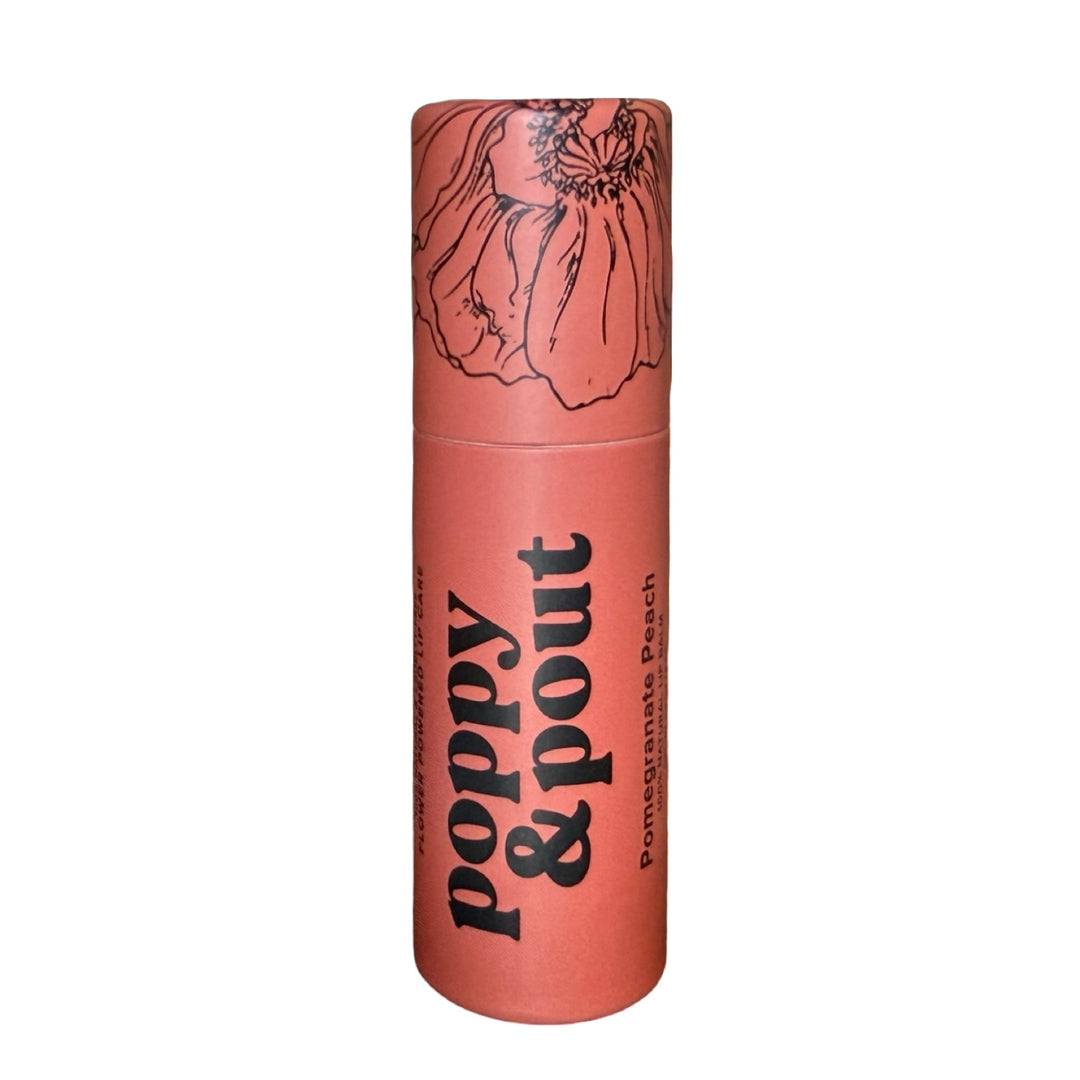 Orange tube of lip balm labeled “poppy & pout" has black thin line floral design on lid.