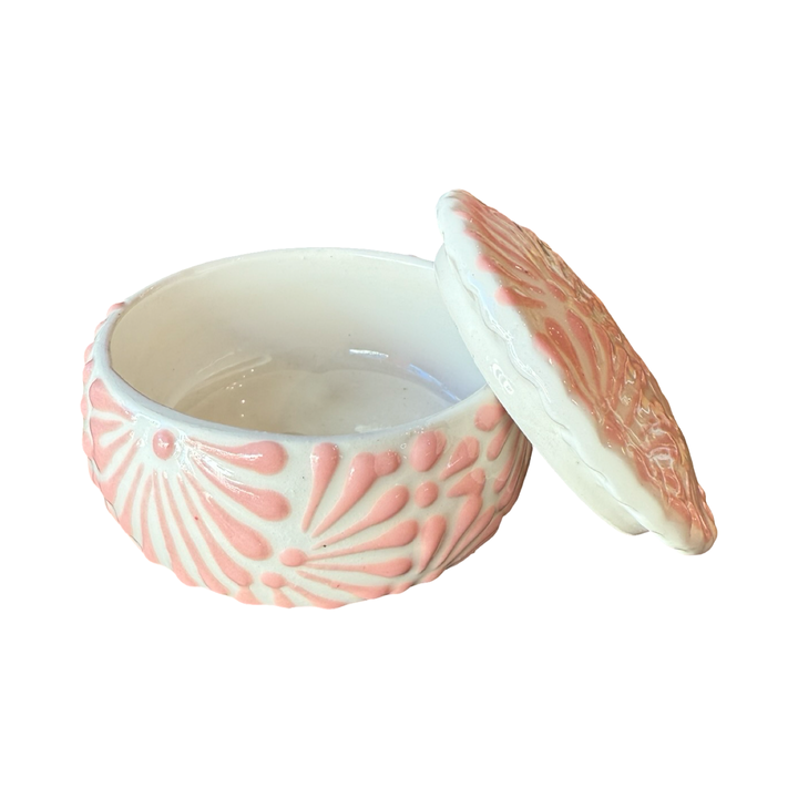 White ceramic lidded container with pink textured talavera design. Photo shows lid leaning against the right edge of the empty container.