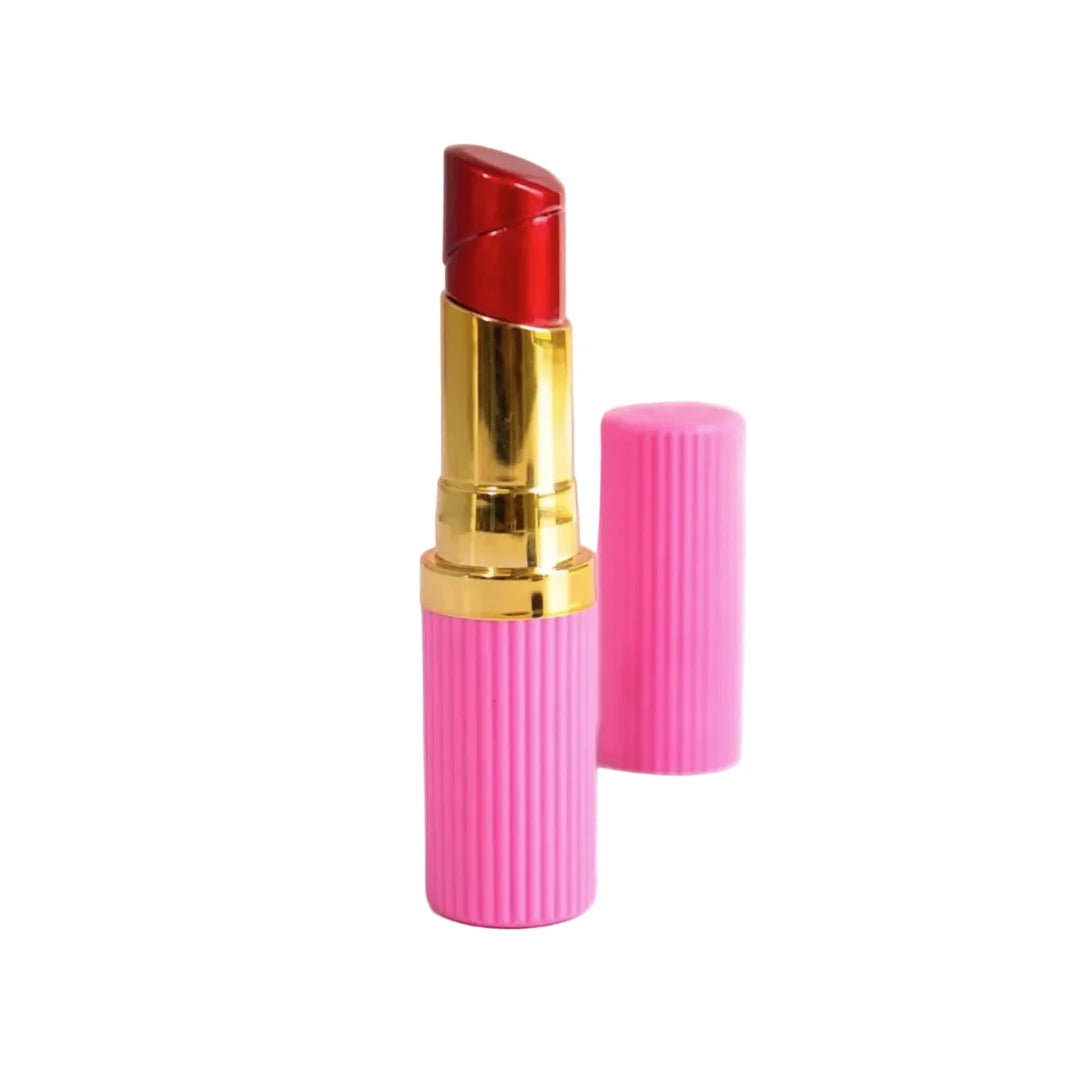 Lipstick shaped lighter with a red metallic tip, gold accent, and ribbed hot pink base beside its matching cap.