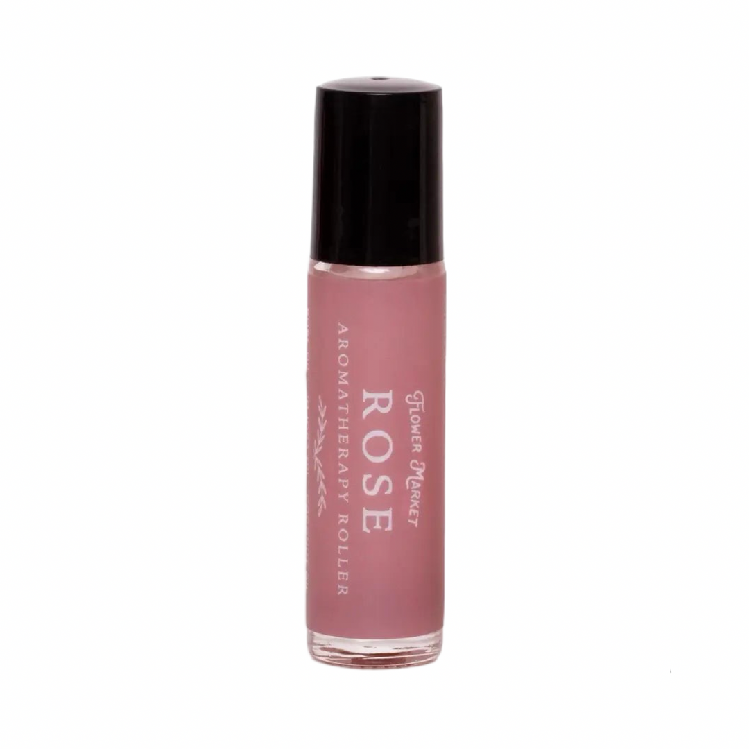 A pink glass aromatherapy roller bottle labeled Rose by Flower Market with a black cap.