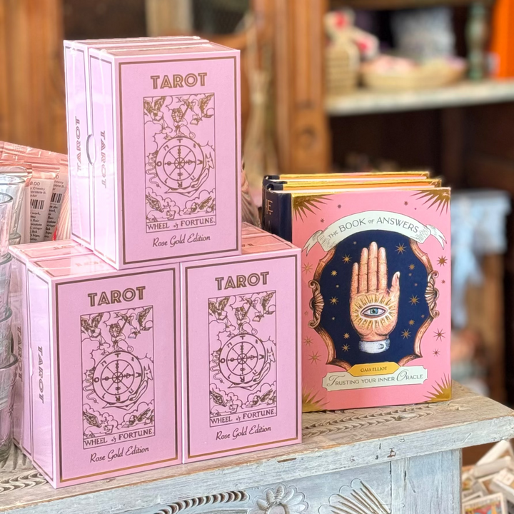 Pink tarot card boxes on a table with a blurred background of a store interior.