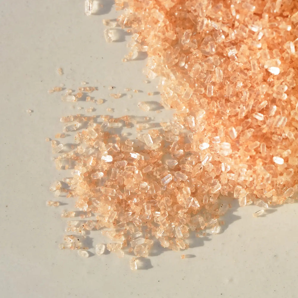 Enhanced view translucent peach mineral bath soak crystals.