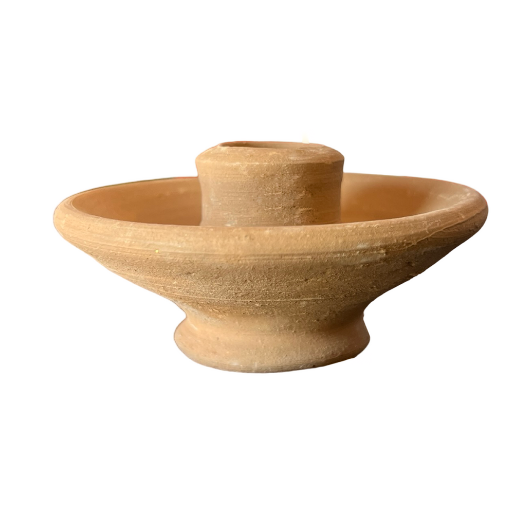side view of A simple, round, handcrafted terracotta clay candle holder with a central holder for a taper candle and a wide base
