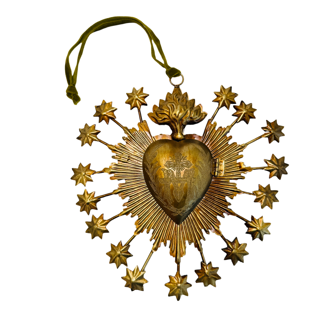 A gilded metal sacred heart locket box with a radiating sunburst, star-tipped rays, and flame topper. Green Velvet ribbon for hanging visible.