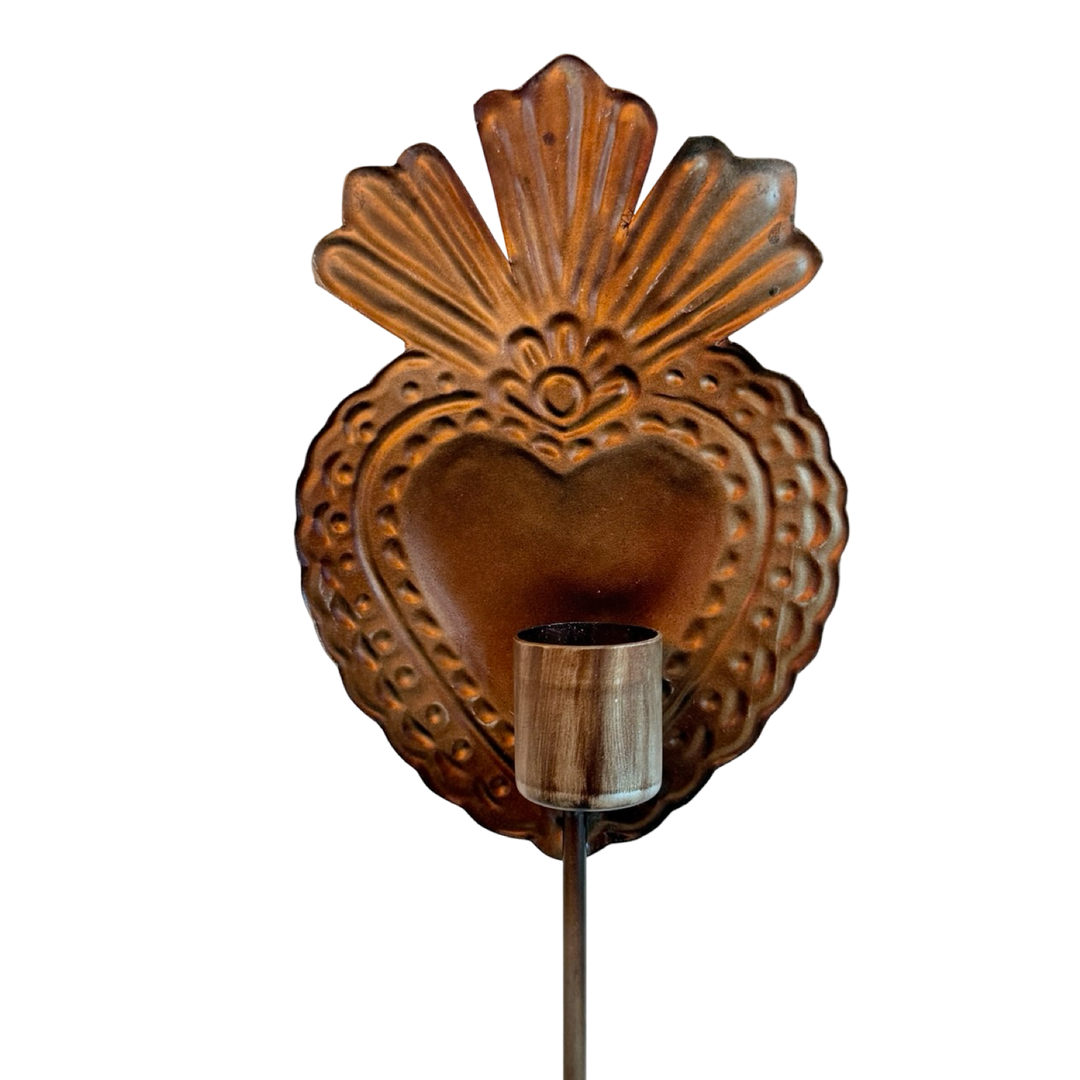Close up image of a bronze-toned candle holder shaped like a sacred heart with a scalloped design at the top with a round candle holder.
