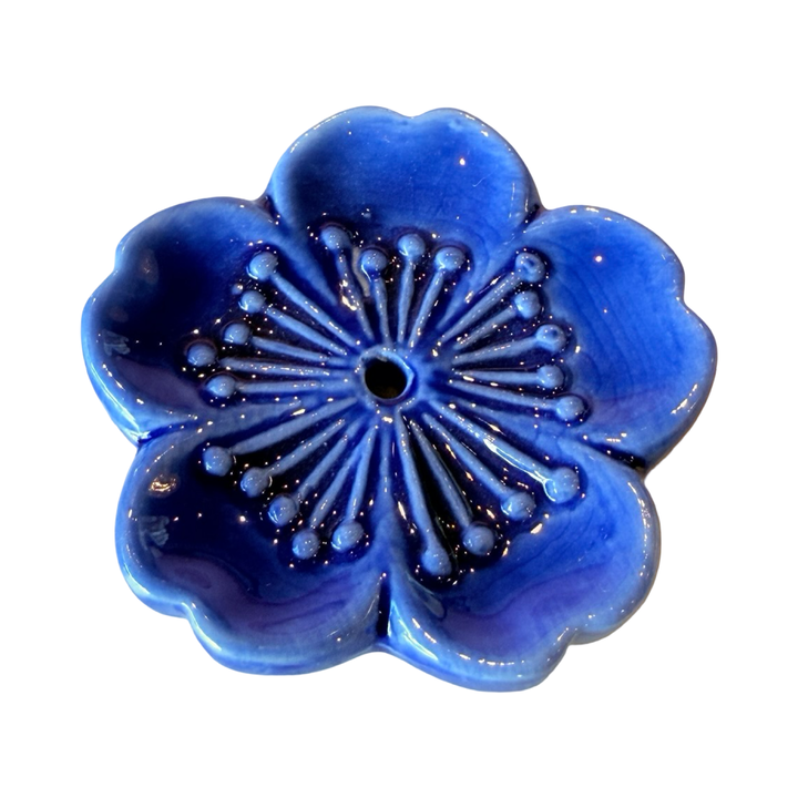 Blue ceramic cherry blossom incense holder with small hole in the center to hold the small end of an incense stick.