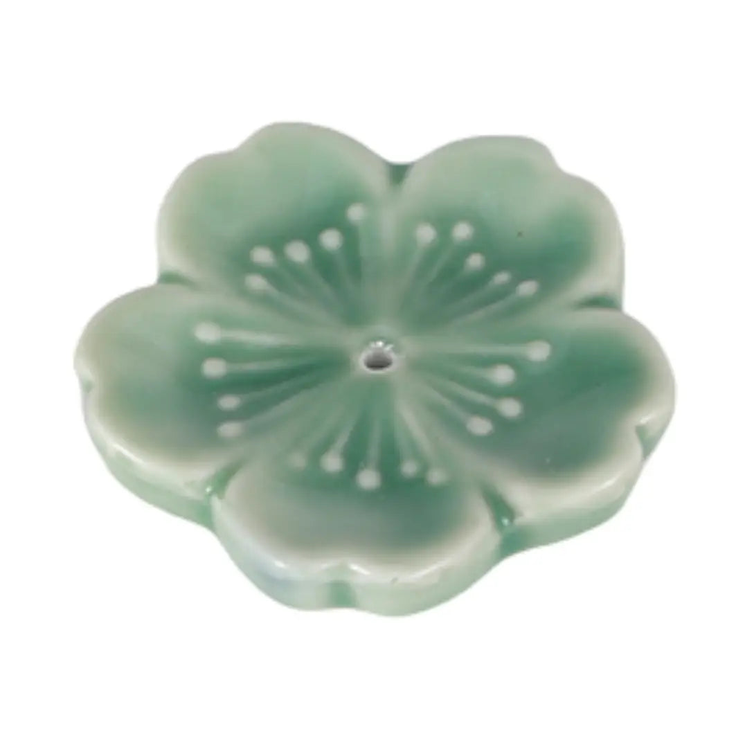 A light green ceramic flower-shaped incense holder with a central hole, featuring a glossy finish and dot details radiating from the center.