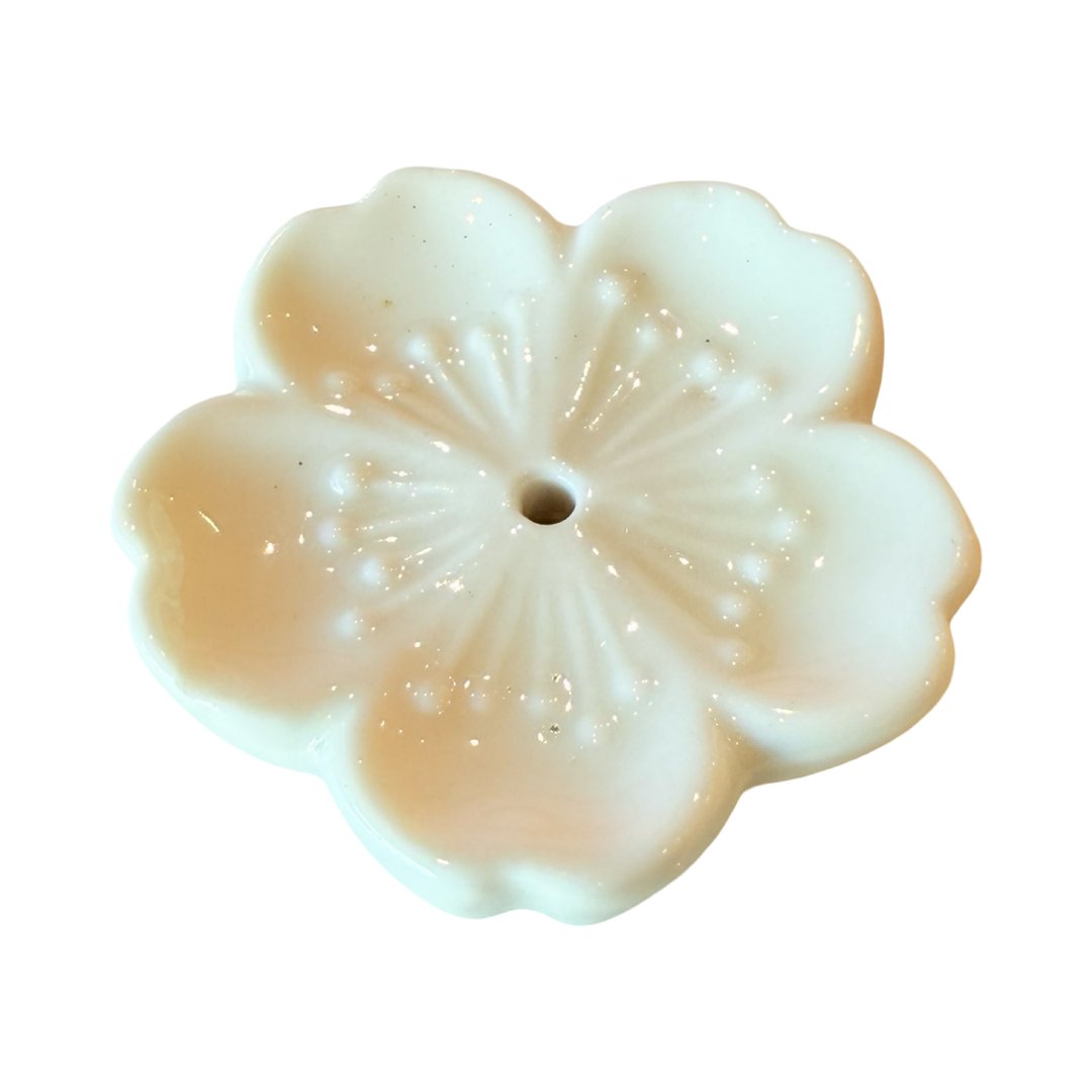 White ceramic cherry blossom incense holder with a small hole in the center to hold the end of an incense stick.