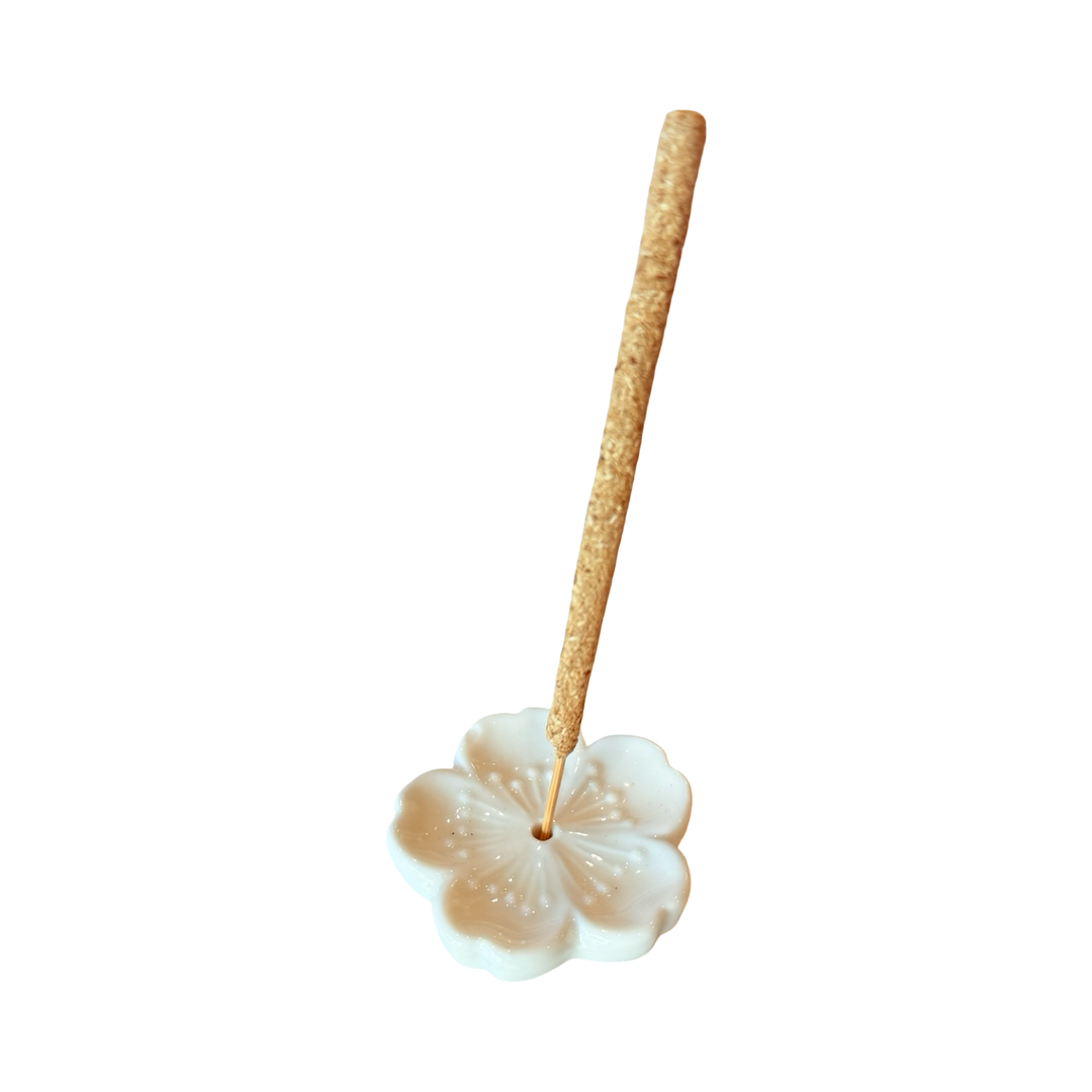 White ceramic cherry blossom incense holder with an incense stick.