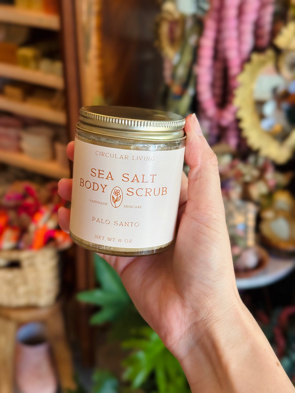 Hand holding a jar of Sea Salt Body Scrub with a blurred store background
