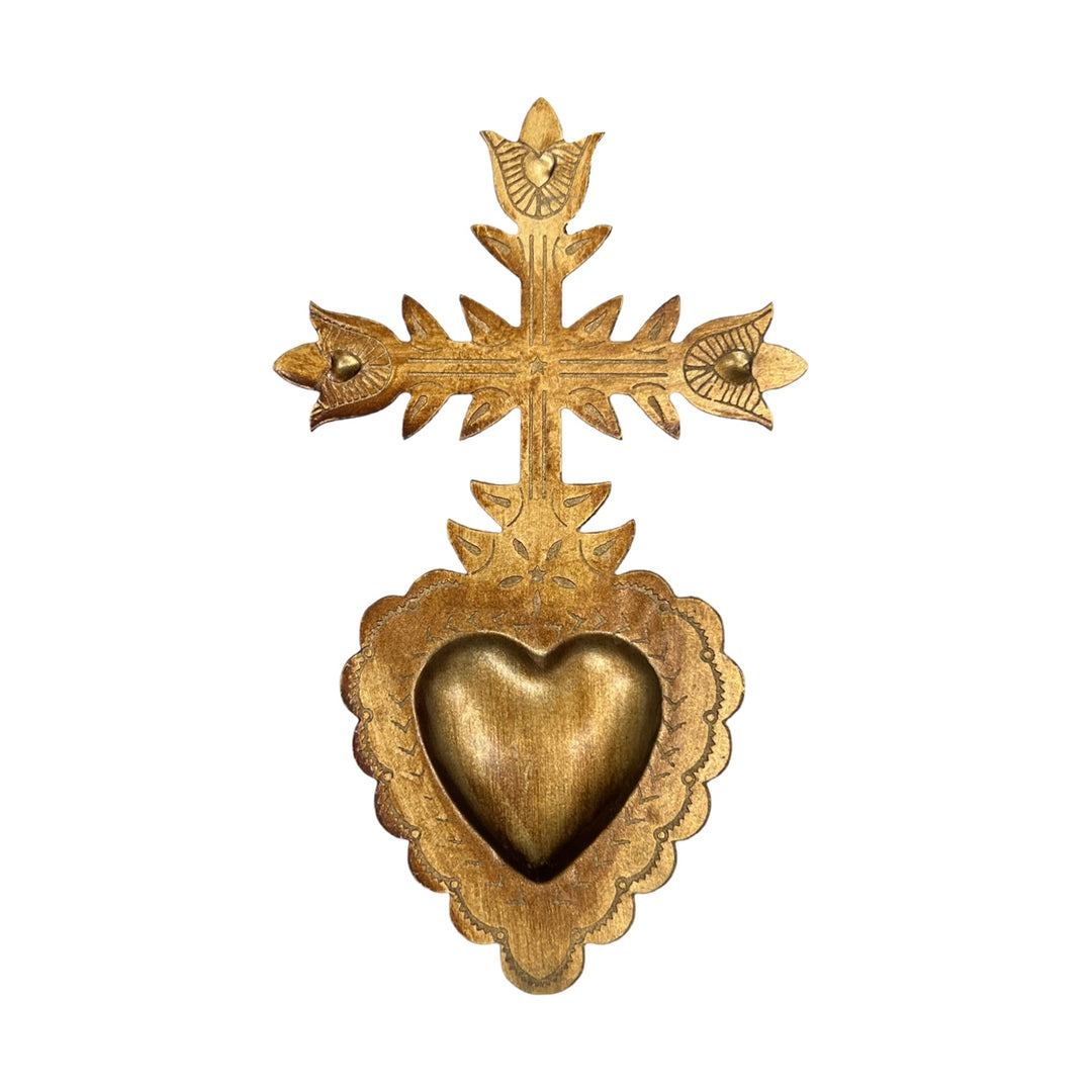 A bronze colored tin ornament in the shape of a cross with a heart design in the center