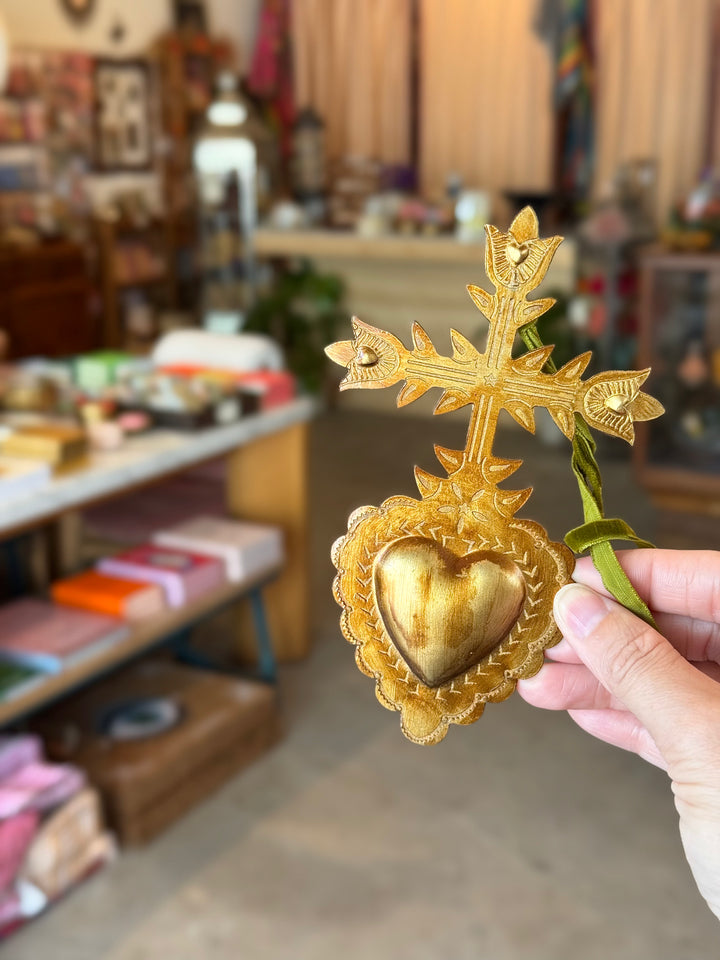 Gold heart-shaped cross held by a hand in a store setting