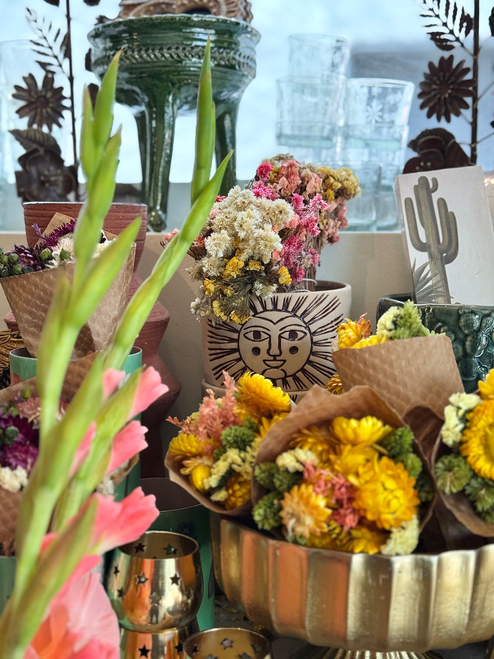 Decorative display with flowers, pots, and a sun face design in a home setting.