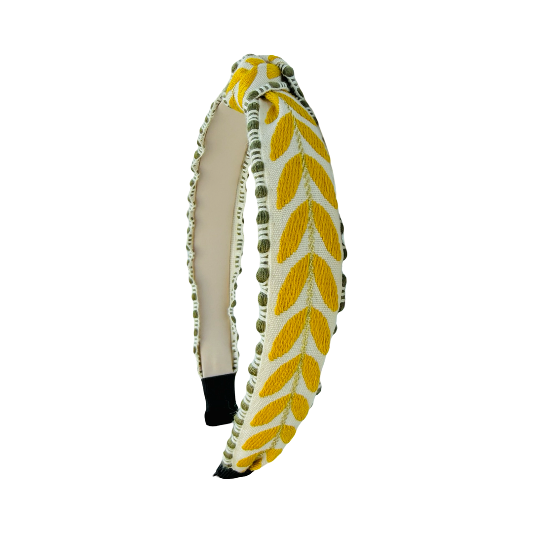 side view of a Slim embroidered headband with yellow leaf pattern and green trim on structured band.