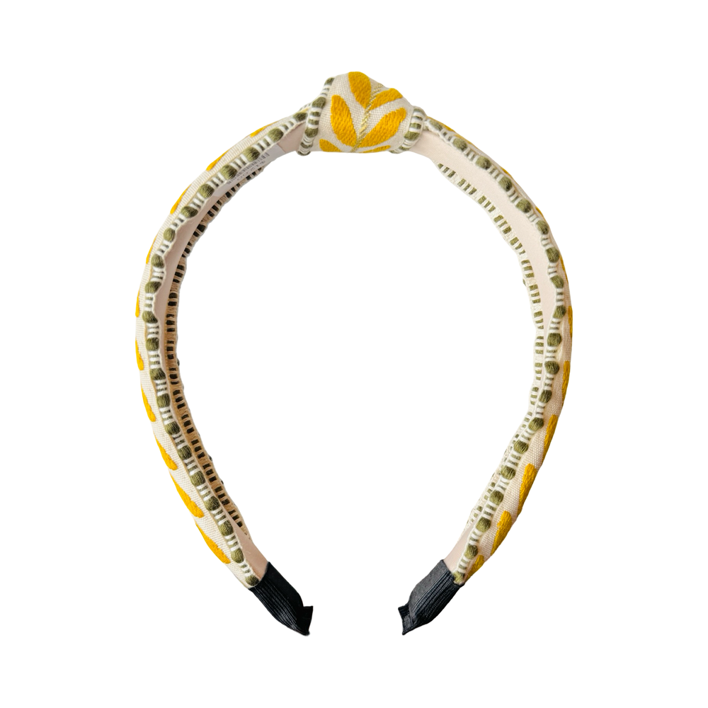 Side view of slim embroidered headband with yellow leaf pattern and green trim on structured band.