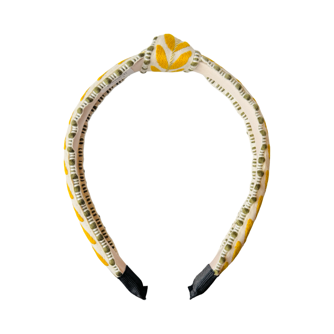 Side view of slim embroidered headband with yellow leaf pattern and green trim on structured band.