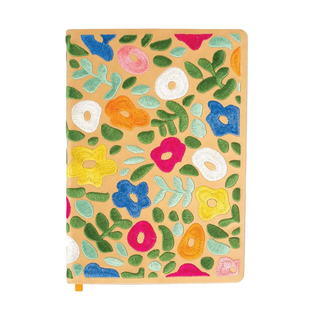 Journal with a tan cover featuring colorful embroidered flowers and green leaves arranged in a scattered garden pattern.