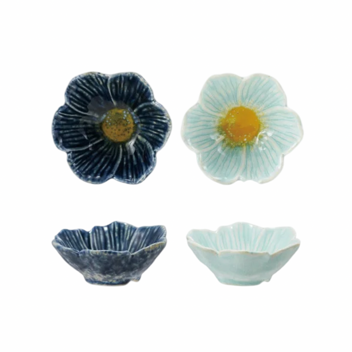 Two stoneware flower-shaped bowls shown from top and side view, in navy blue and mint, each with a yellow center glaze.