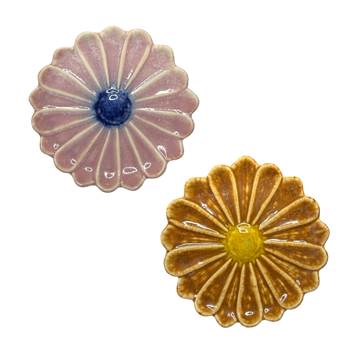 set of two flower shaped plates: one pink with a blue center and the other is brown with a yellow center.