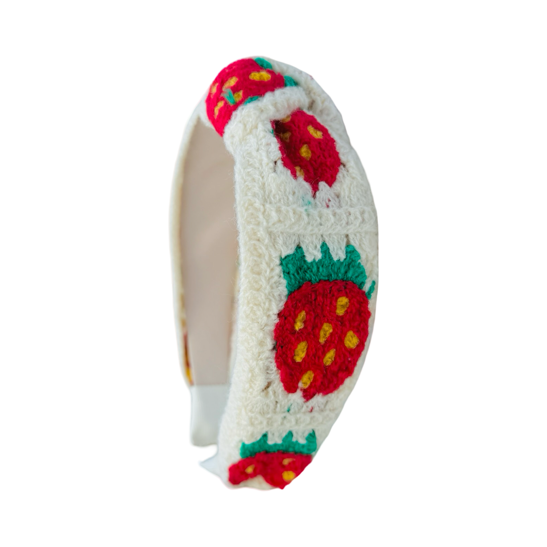 side view of a Padded cream crochet headband with red strawberry pattern and knotted top detail.