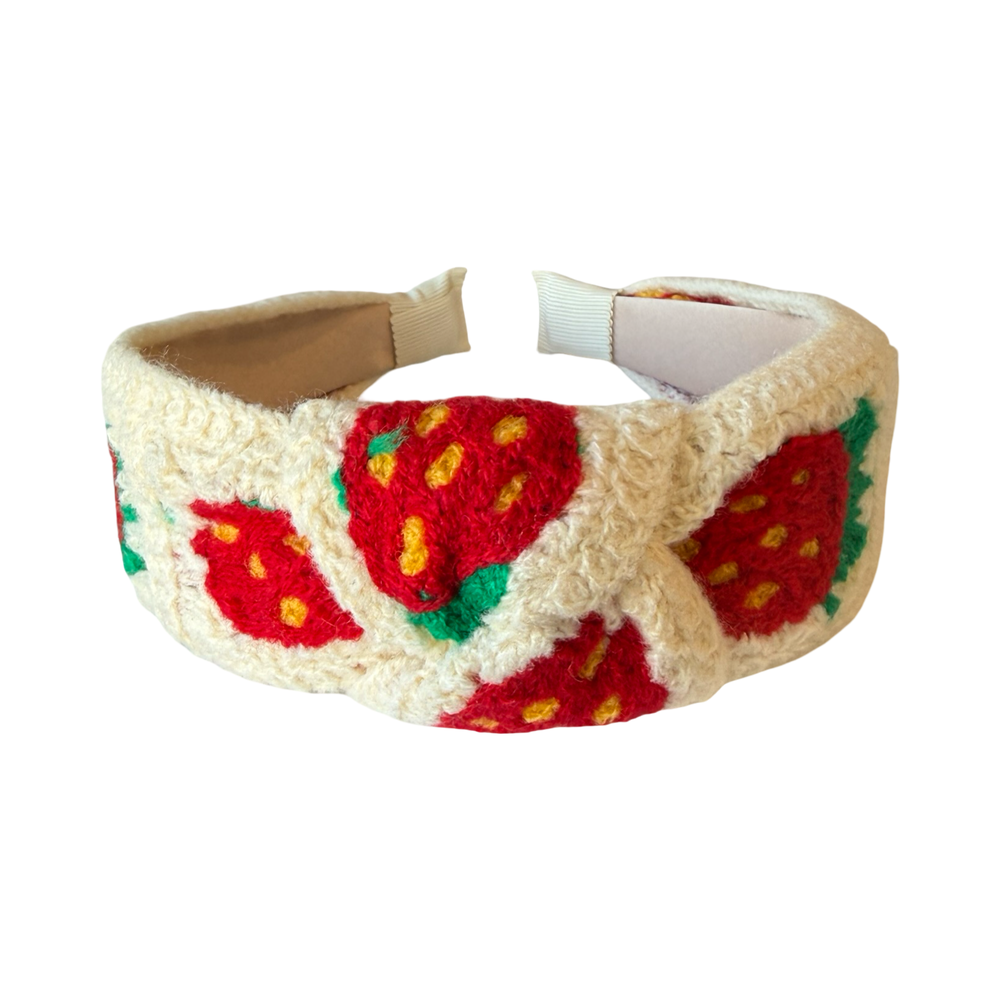 top view of a Padded cream crochet headband with red strawberry pattern and knotted top detail.