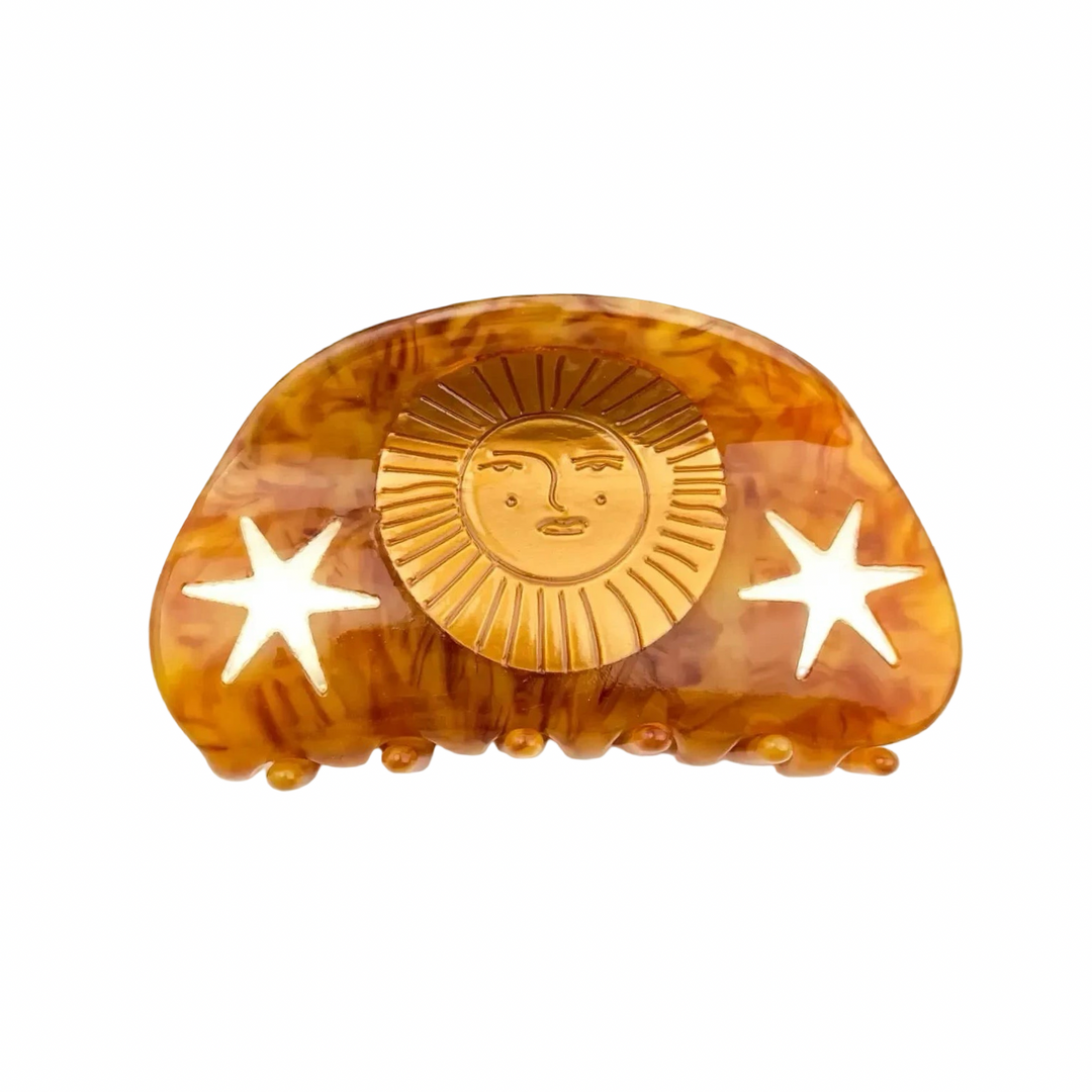 Tortoiseshell hair claw clip with a carved sun face and star cutouts.