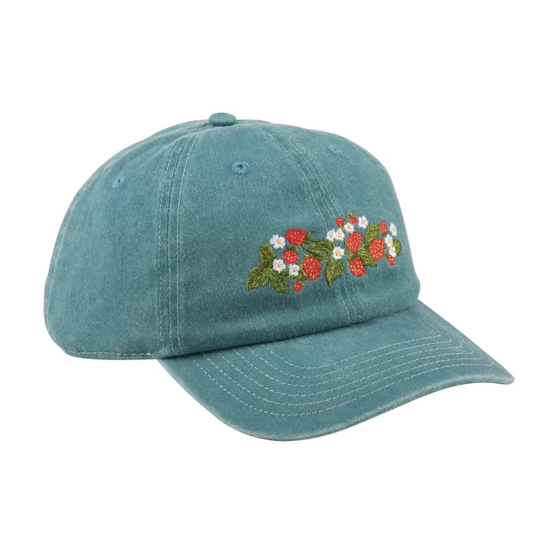 A washed teal baseball cap with an embroidered strawberry and daisy botanical design on the front panel.
