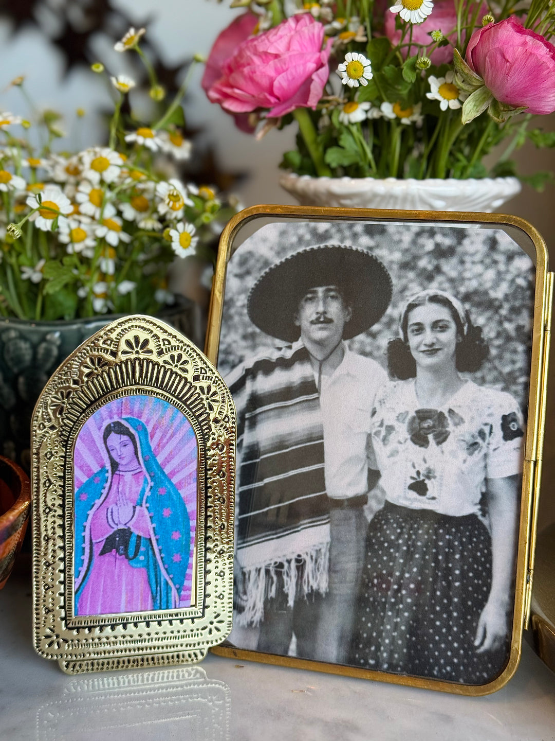 Decorative item with a religious icon and a vintage photo of a couple with flowers in the background.