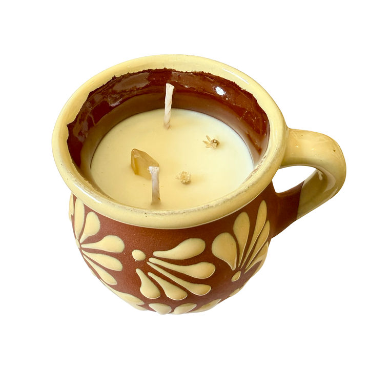 top view of a terracotta mug with a cream design and rim featuring dried flowers and crystals.