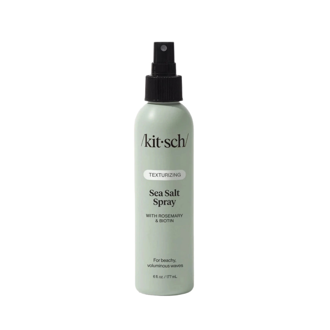 7 oz Light green bottle of Kitsch Texturizing Sea Salt Spray with a black spray nozzle, labeled with rosemary and biotin for beachy, voluminous waves.