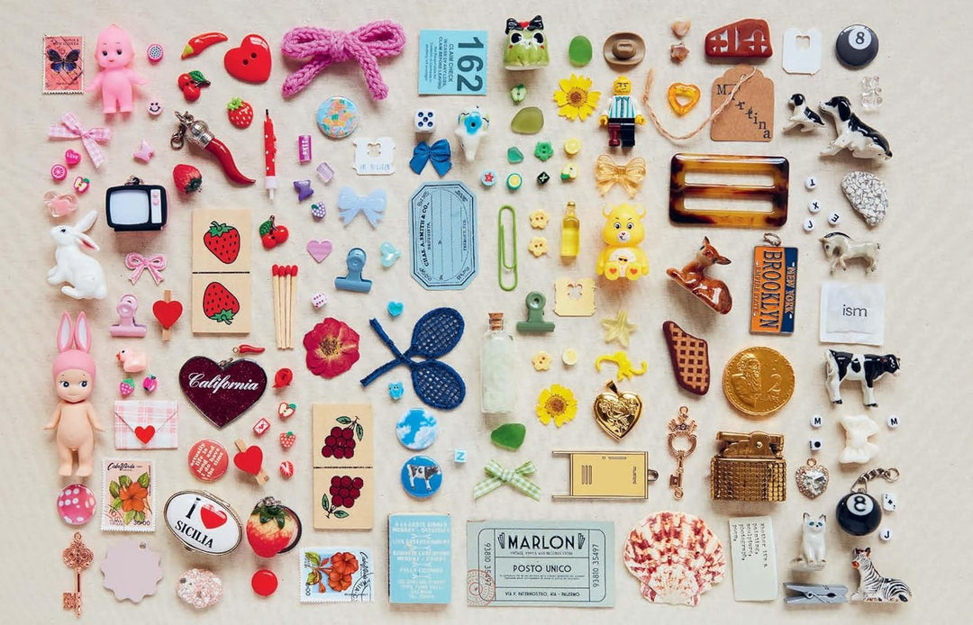  A book page displays image of small momentos such as decorative pins, charms, figurines, toys, tags, and more organized in a colorblocked style going from pink to red to blue to green to brown to black and white. 