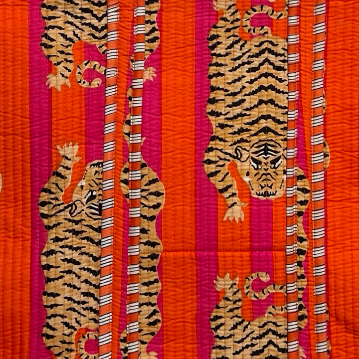 close up view of an orange and black tiger print on a pink and orange striped background.