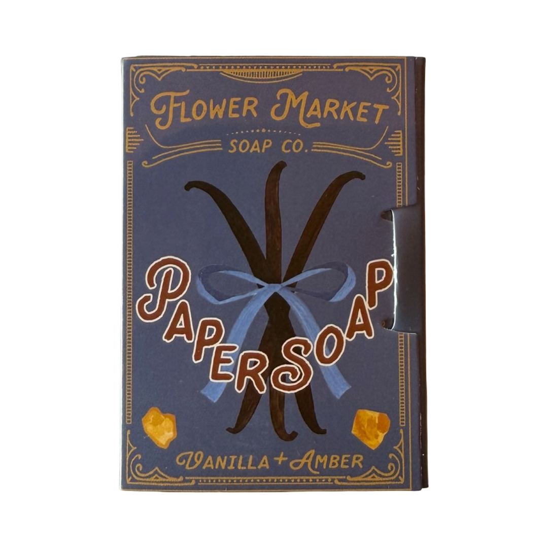 Vanilla + Amber Paper Soap in a dusty blue matchbook style case with painted vanilla beans tied in a blue bow and amber pieces