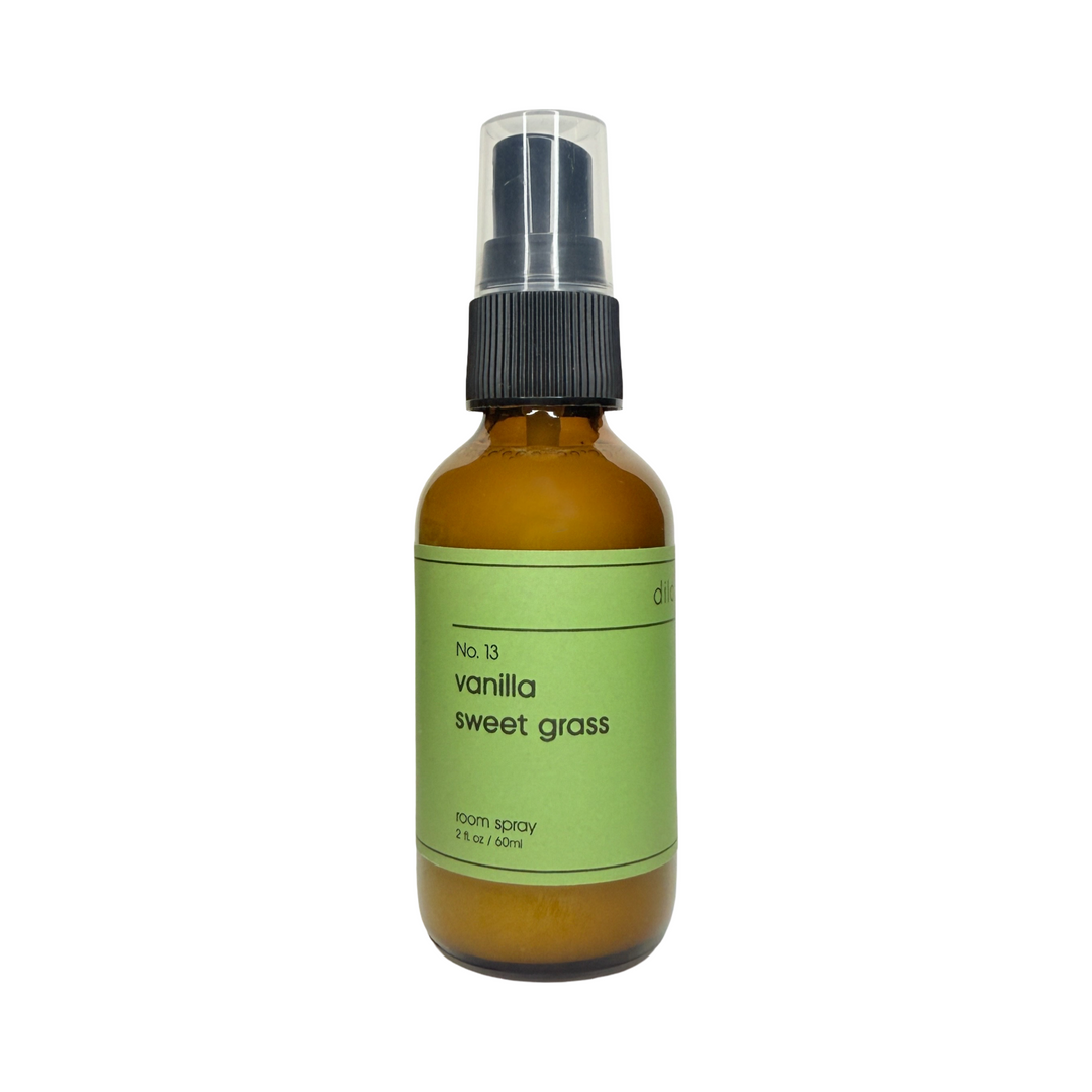 2 oz brown glass bottle of vanilla sweet grass room spray with a green branded label.