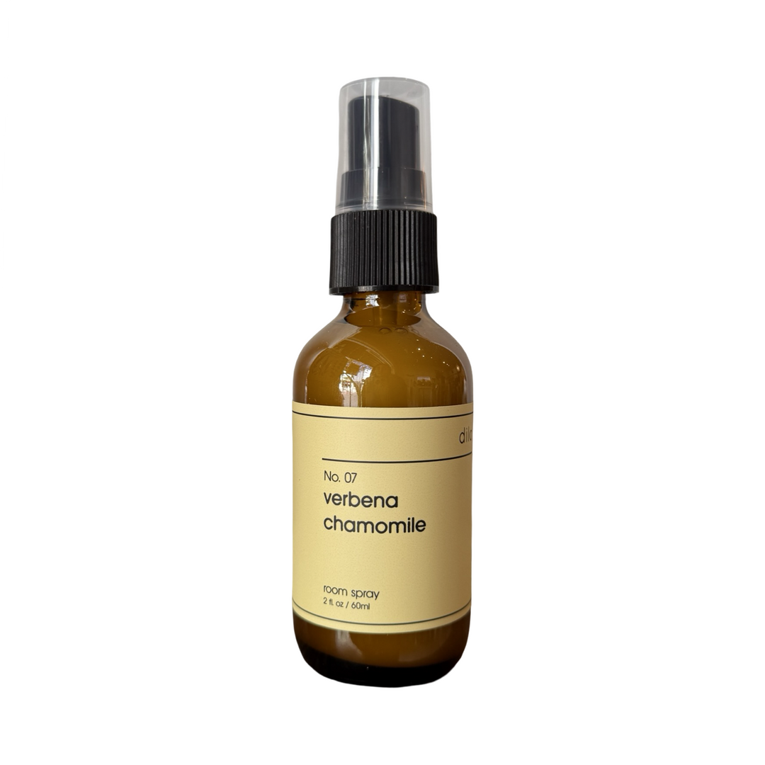 a 2 oz dark brown bottle of verbena chamomile room spray featuring a pastel yellow label with a black pump.
