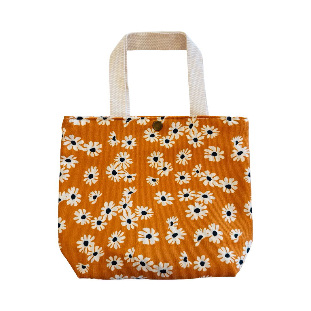 Mini orange corduroy tote bag with small floral print, fabric handles, and a snap closure.