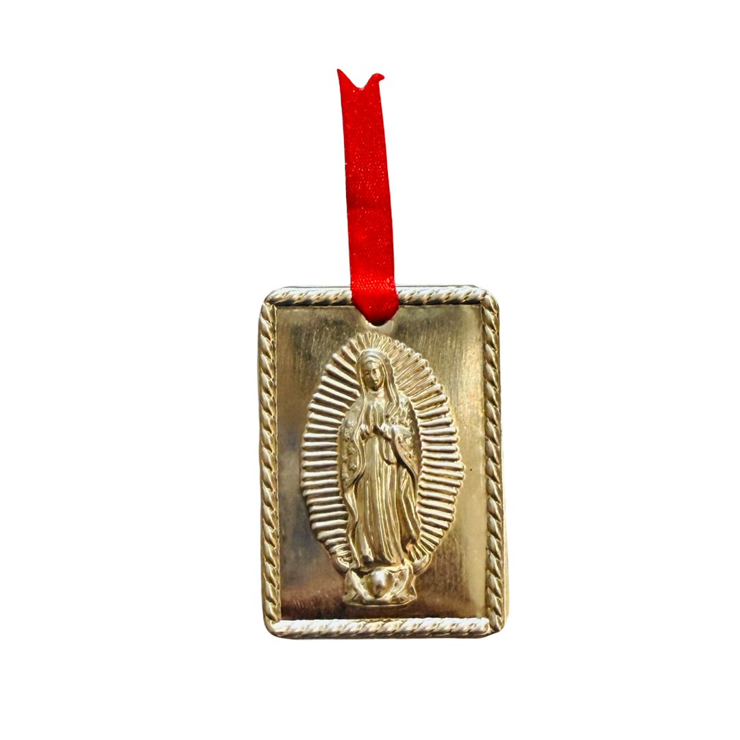 milagro features Our Lady of Guadalupe in raised relief, framed by a twisted rope border and finished with a red ribbon.