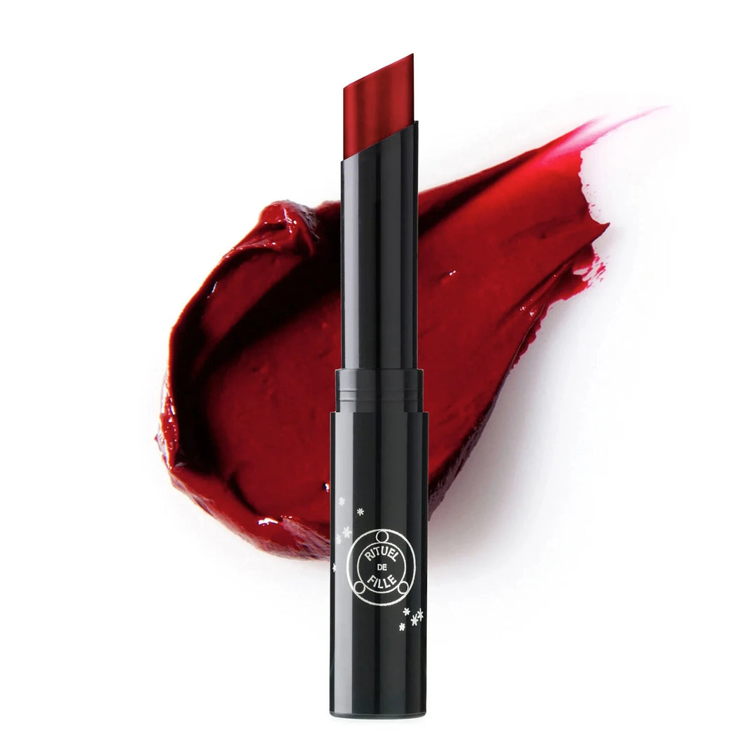 black branded tube of red shade lipstick with a color swatch behind it. Brand: Rituel De Fille