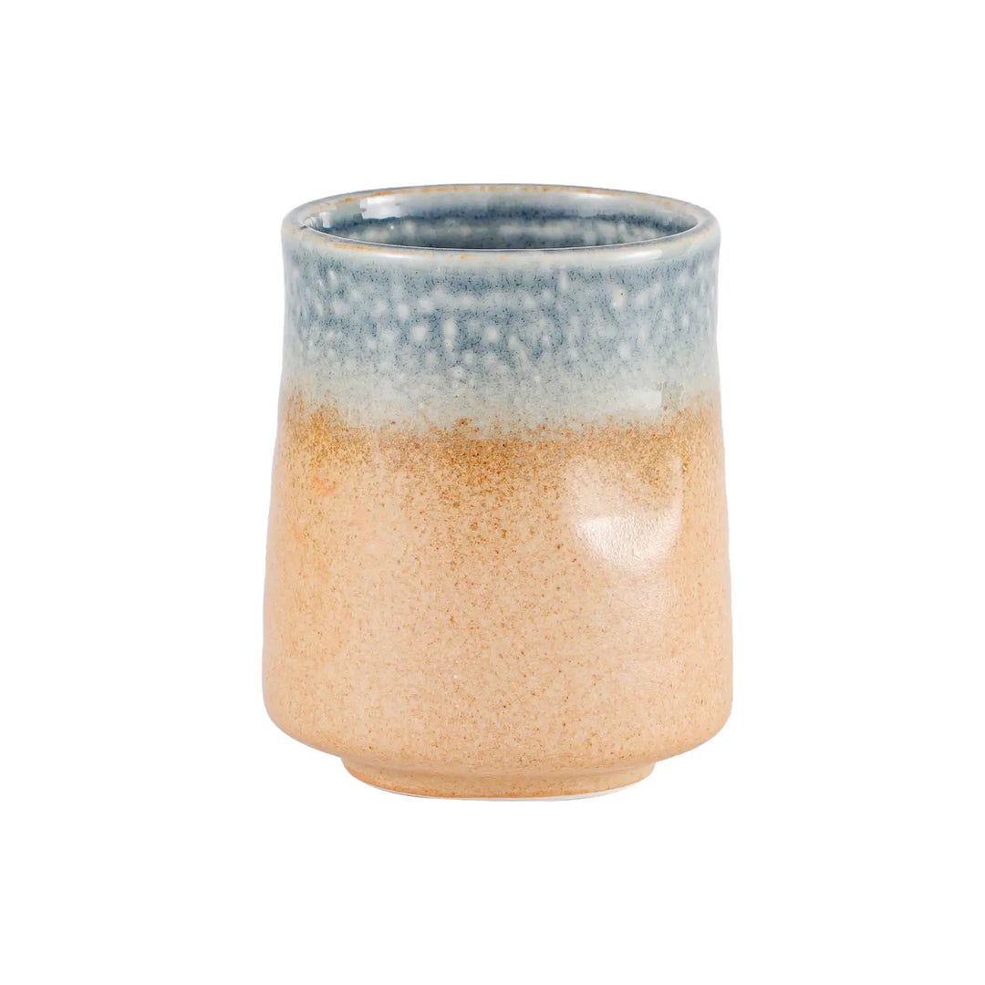 Small stoneware yunomi cup with sandy tan body and speckled blue rimmed glaze on a short footed base.